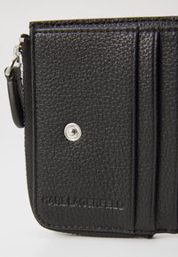 Μαύρος δερμάτινος κωδικοποιητής με υφασμάτινη επιφάνεια, ασημένιο κουμπί με κούμπωμα και ανάγλυφο όνομα επωνυμίας "KARL LAGERFELD" στην μπροστινή πλευρά.