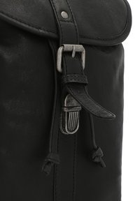Bolso de cuero negro con una tapa redonda, herrajes de metal y una correa ajustable con cierre de clip. Textura suave con detalles de costura.