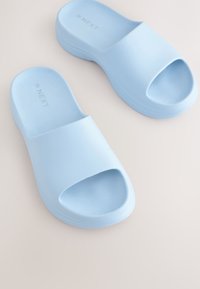 Sandales à glissière bleu clair en plastique lisse, avec un design à bout ouvert, une large bride sur le dessus et une semelle légèrement profilée.