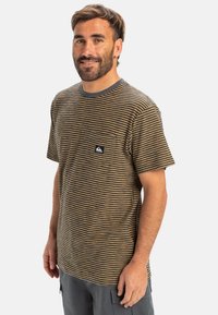 Gestreepte T-shirt met korte mouwen in bruin en mosterd, met een ronde hals en een borstzak met een logo label. Zachte stoftextuur.