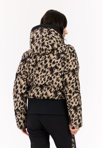 Gewatteerde jas met een zwart, beige en bruin dierenprint, voorzien van een capuchon en een aansluitende zwarte onderband. Soepele textuur, warme uitstraling.