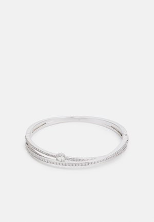 Ezüst karkötő, amely két párhuzamos sávból áll, az egyik kis tiszta drágakövekkel díszített, középen pedig egy sima kör alakú kiemeléssel.