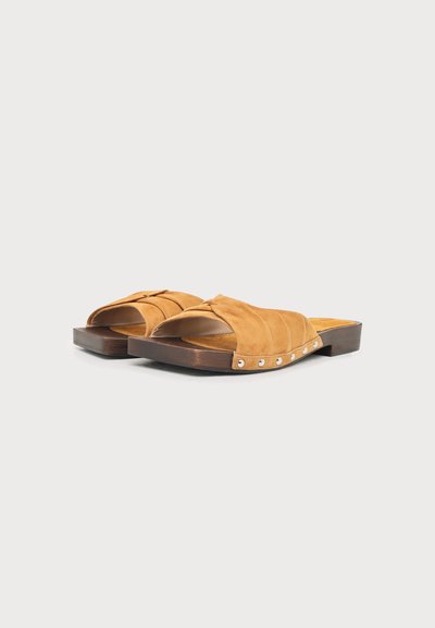 Paire de sandales en daim marron à bout ouvert, à enfiler, avec semelles en bois et petits clous métalliques le long des côtés.