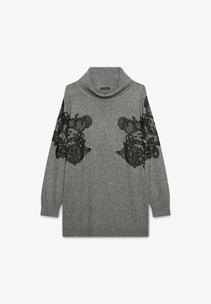 Suéter gris con cuello de cisne, que presenta detalles de encaje negro en las mangas. Textura suave, corte relajado y mangas largas y sueltas.