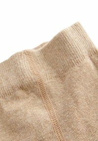 Calze beige lavorate a maglia con una texture a coste e una finitura liscia. Presentano una cucitura centrale e una vita morbida per il massimo comfort.