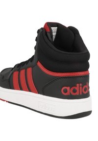 Czarne sneakersy typu high-top z czerwonymi akcentami i trzema paskami, wykonane z materiału syntetycznego o fakturowanym wykończeniu i białej gumowej podeszwie.
