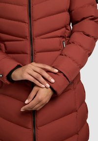 Rote Stepp-Wattierte Jacke mit Reißverschluss vorne, elastischen Bündchen und einer Reißverschlusstasche am Ärmel. Glatte Stofftextur.