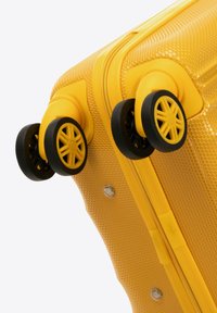 Geel koffertje met een gestructureerd oppervlak, twee zwarte multidirectionele wielen, een stevige rits en versterkte hoeken voor duurzaamheid.