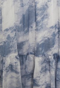 Tecido padrão azul e branco com um acabamento suave e texturizado. Apresenta camadas fluídas, que se assemelham a um design em aquarela com motivos semelhantes a nuvens.