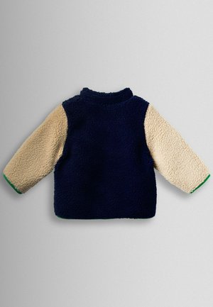 Fleece pullover med navyblå krop, beige ærmer og grøn kant. Har høj krave og en tekstureret overflade.