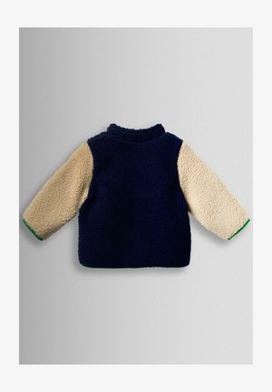 Flis pulover s tamnoplavim tijelom, bež rukavima i zelenim rubom. Ima visoki ovratnik i teksturiranu površinu.