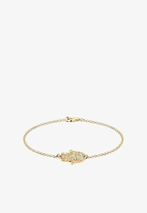 Aukso grandinėlė su apyranke, kuri turi rankos formos pakabuką, papuoštą blizgančiais akmenukais, demonstruojančiu sudėtingus rašymo elementus ir vėrinio užsegimą su krabuko užsegimu.