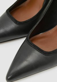 Mustad nahast teravate otstega kingad madala lõikega; sile ülemine pind matt viimistlusega ja beež sisemine vooder.