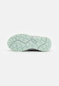 Lichtgrijze zool van een wandelschoen met een getextureerde mintgroene rubberen buitenzool met diepe profiel voor grip en stabiliteit.