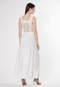 Maxikleid in Weiß, mit einem Häkelrücken, ärmellosem Schnitt und gestuften Saum, mit fließender Textur und tailliertem Bund.