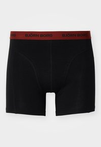 Black boxer shorts made from soft fabric, featuring a red elastic waistband with "BJÖRN BORG" logo, and fitted design with a low-rise cut.