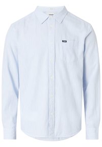 Camicia azzurro chiaro con sottili righe bianche, taschino singolo sul petto e orlo arrotondato. Realizzata in tessuto dalla texture liscia.