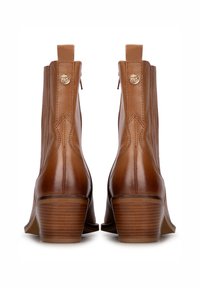 Brown leather ankle boots with a rounded toe, vertical stitching, and a low stacked heel. Features a small gold emblem and rear pull tabs.