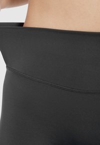 Leggings noirs taille haute avec une texture lisse, dotés d'une large ceinture élastique et de coutures à plat pour le confort et la durabilité.