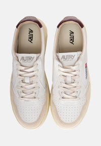 Sneakers bianchi in pelle con tallone bordeaux, rifiniture beige, punta forata e lacci piatti. Presentano il logo sulla linguetta e sul lato.