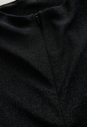 Detailní záběr na černou látku s viditelným zipem a jemně lesklou strukturou, která zdůrazňuje límec a detaily švů oděvu.