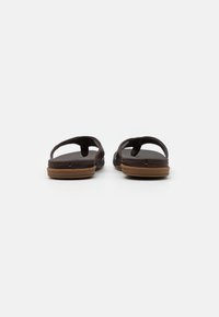 Bruine flip-flops met platte zolen, voorzien van een gestructureerde voetbed, brede straps en een minimalistisch ontwerp. Stijlvolle hardware accenten op de straps.