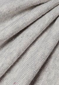 Hellgrauer Strickstoff mit einer gerippten Textur, der weiche Fasern und ungleichmäßige Garne aufweist, was subtile Farbnuancen erzeugt.