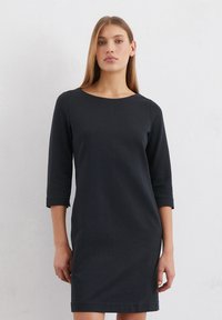 Zwarte jurk tot de knie met driekwart mouwen, ronde halslijn en een gladde textuur, met een eenvoudig ontwerp en zonder zichtbare patronen.