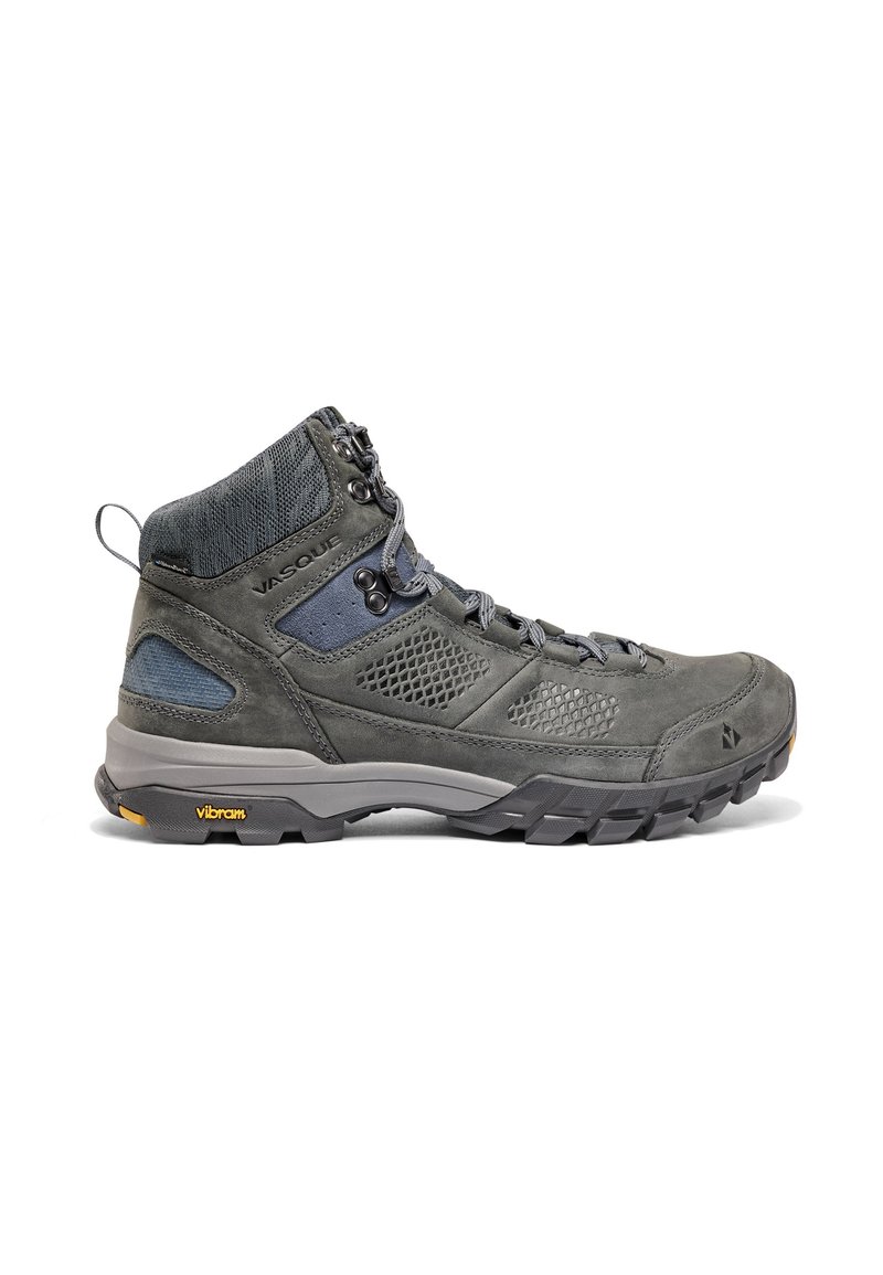 Bota de senderismo gris que combina materiales de cuero y malla, con soporte alto para el tobillo, acentos texturizados y suela Vibram para mayor tracción.