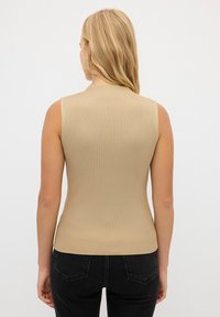 Top senza maniche beige a coste, design aderente, texture liscia, scollatura rotonda, privo di hardware visibile o decorazioni.