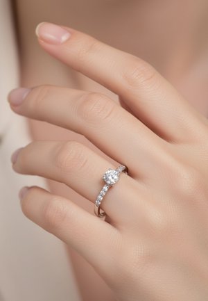 Anello di fidanzamento in argento con un diamante centrale rotondo, arricchito da diamanti più piccoli lungo la fascia. Finitura liscia e lucida.