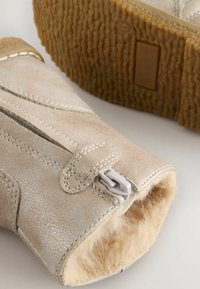 Beiga läderankleboots med en texturerad yta, vita sömmar, dragkedja framtill och en mjuk innerfoder av päls. Gummisula.
