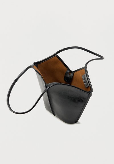 Μαύρη δερμάτινη τσάντα χειρός με απαλή υφή και εσωτερικό σε αντίθετο καφέ χρώμα. Διαθέτει έναν μαύρο ιμάντα και κούμπωμα με κλιπ.