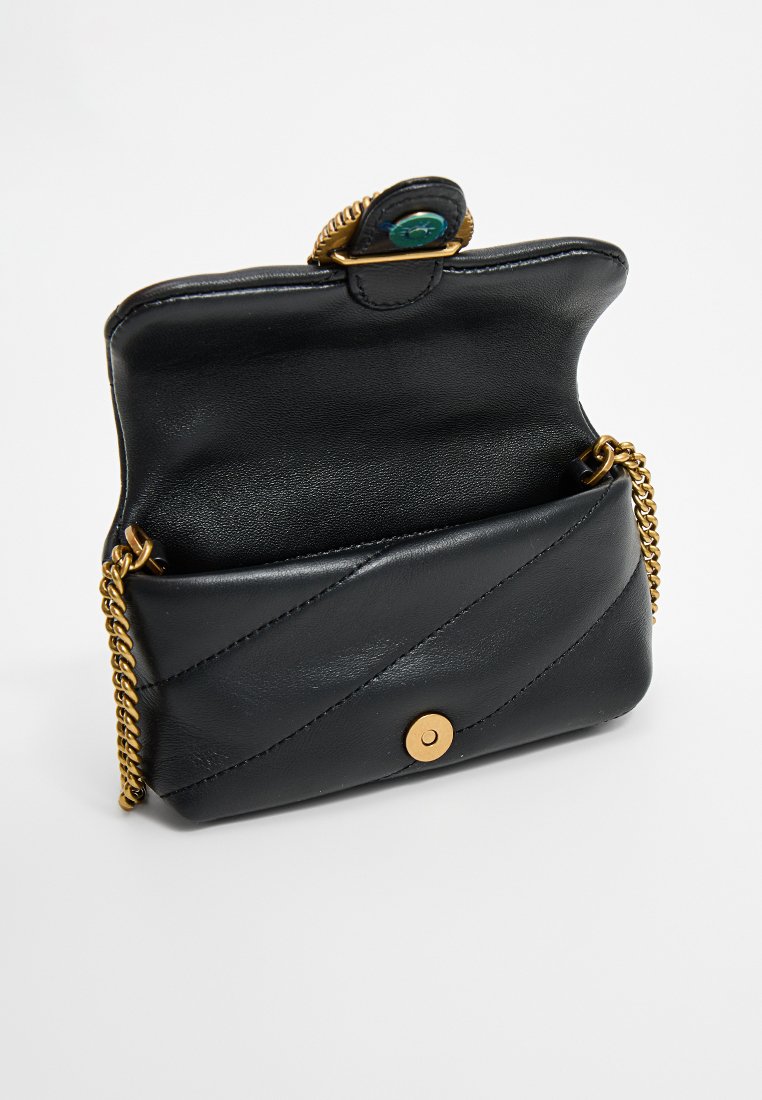 Petit sac à main en cuir noir avec un motif matelassé, rabat ouvert, fermoir magnétique doré et bandoulière en chaîne dorée sur un fond blanc.