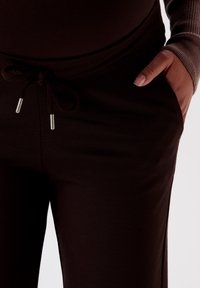 Braune Jogginghosen mit einem Kordelzugbund mit silbernen Metallenden, Seitentaschen und einem weichen, dehnbaren Stoff für optimalen Komfort.