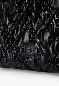 Material negro brillante acolchado con un pequeño parche que presenta un emblema de calavera y huesos cruzados negros cosido en la superficie.