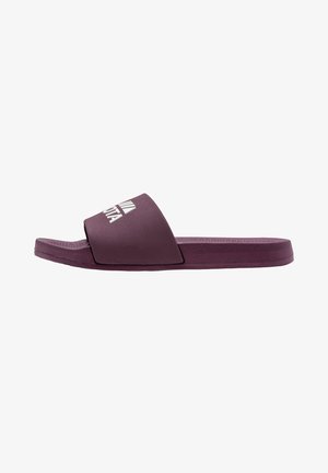 Purple slide sandal with a flat sole, broad strap, and textured insole. Features a white logo on the strap, made from flexible material.