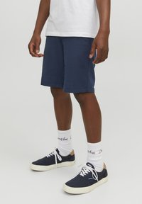 Pantaloni corti blu navy realizzati in tessuto leggero, con vestibilità comoda e design lungo fino al ginocchio, abbinati a calzini bianchi e sneakers blu navy.