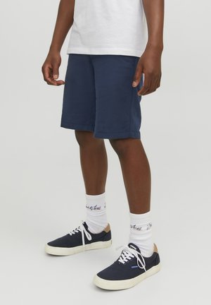 Pantaloni corti blu navy realizzati in tessuto leggero, con vestibilità comoda e design lungo fino al ginocchio, abbinati a calzini bianchi e sneakers blu navy.