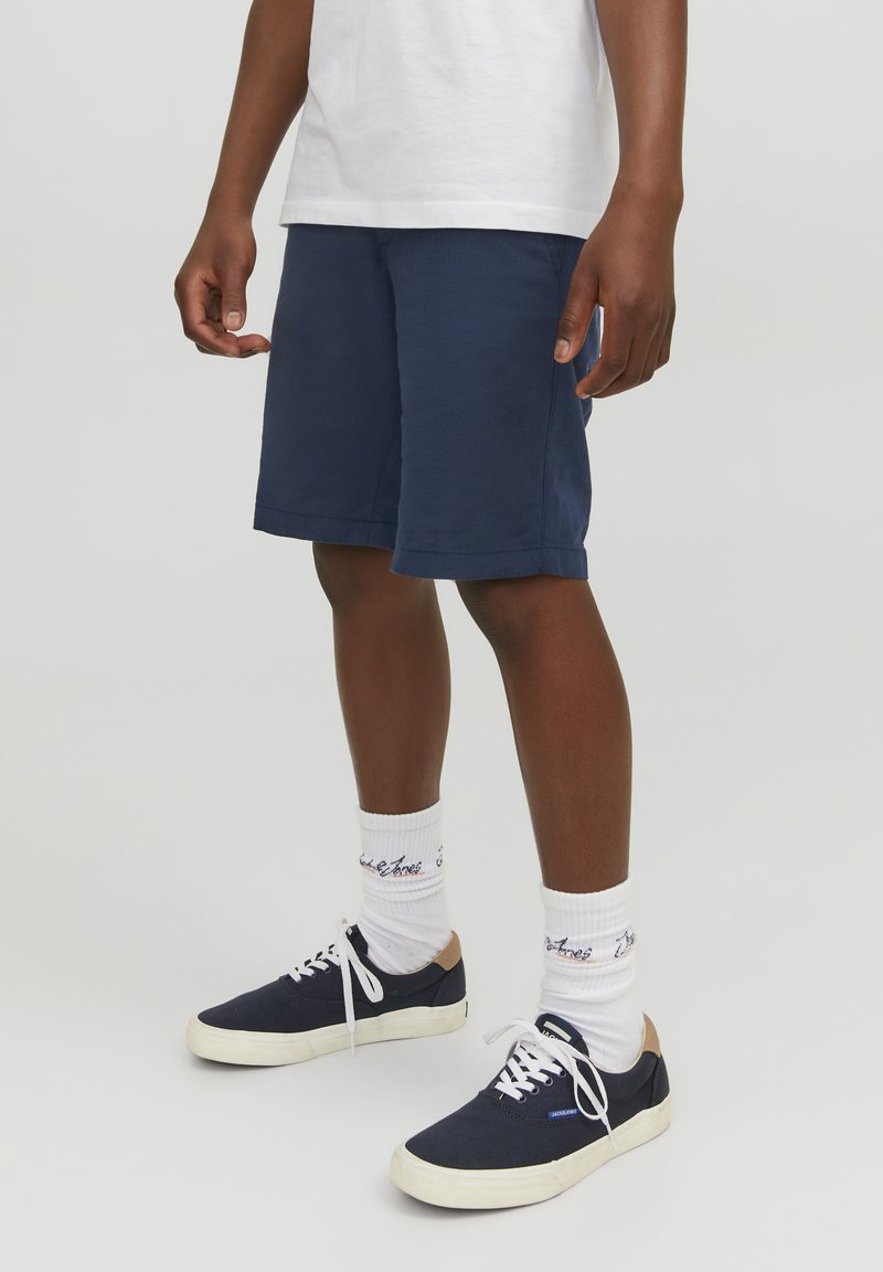 Pantaloni corti blu navy realizzati in tessuto leggero, con vestibilità comoda e design lungo fino al ginocchio, abbinati a calzini bianchi e sneakers blu navy.