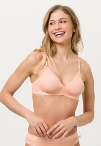 Weicher, rosa drahtloser BH aus glattem Stoff, mit einer V-förmigen Cup und verstellbaren Trägern für eine bequeme Passform.