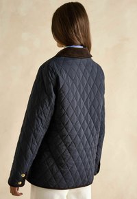 Pikowana granatowa kurtka z brązowym kołnierzem z kordurowej tkaniny, o luźnym kroju, z zatrzaskami i strukturalnym wzorem w romby na materiale.