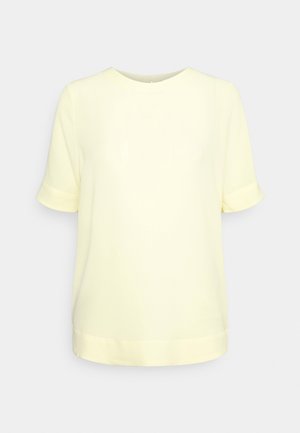 Jasnożółta bluzka z krótkim rękawem, z okrągłym dekoltem i mankietami na rękawach, prezentowana na jednolitym jasnoszarym tle.