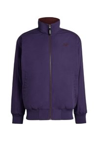 Violetti vetoketjullinen takki, jossa korkea kaulus, resorit hihansuissa ja helmassa, kaksi sivutaskua ja brodeerattu logo rinnassa.