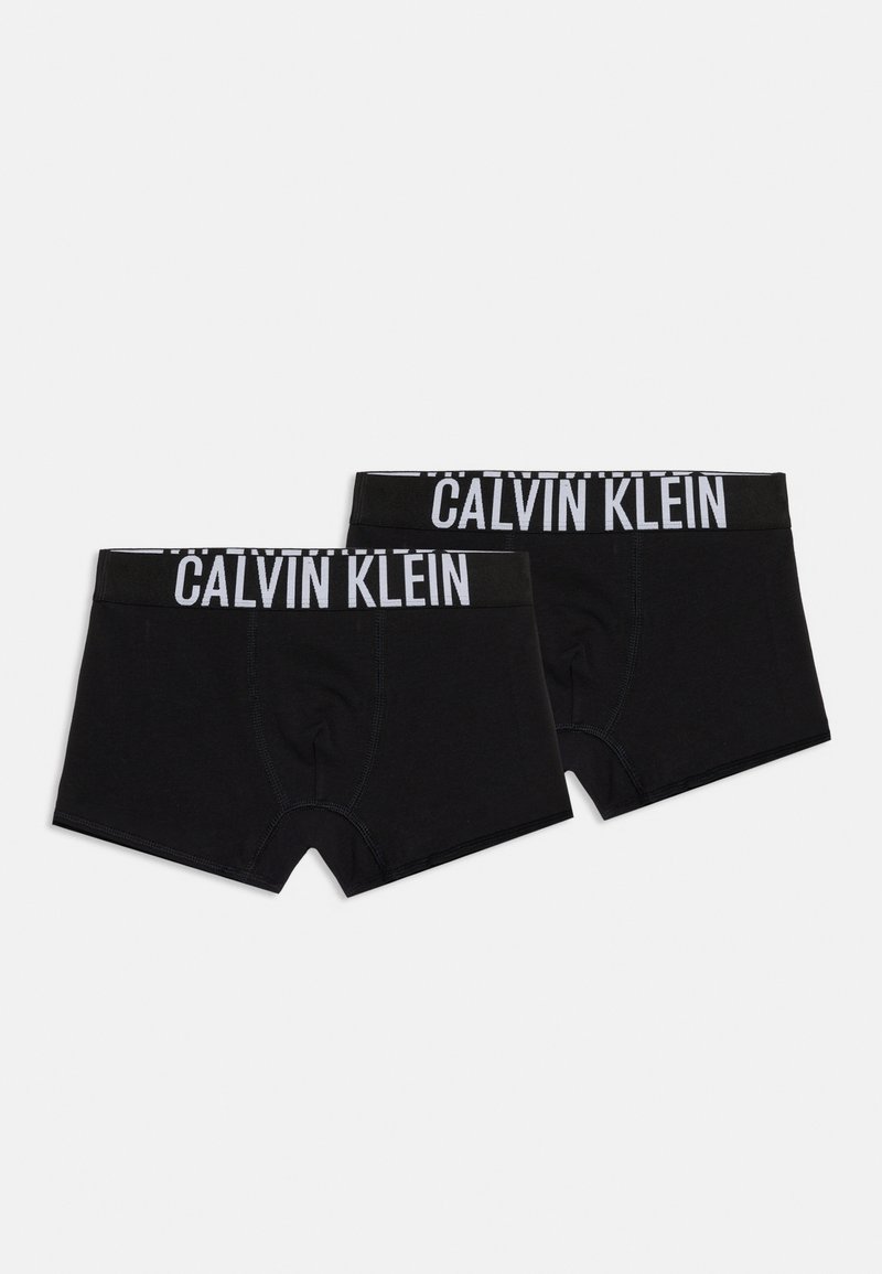 Δύο μαύρα μποξεράκια Calvin Klein με λευκή λωρίδα μέσης με λογότυπο, τοποθετημένα επίπεδα σε λευκό φόντο.
