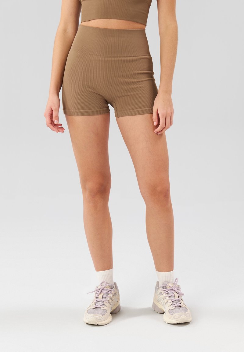 Ensemble de sport marron côtelé comprenant un haut court et un short taille haute, assorti à des chaussures de sport de couleur claire et des chaussettes blanches.
