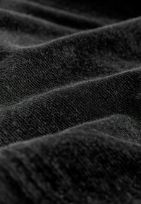 Schwarzer, strukturierten Stoff mit sichtbaren Webmustern und subtiler Weichheit, der leichte Wellen und unterschiedliche Dicken aufweist.