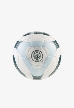 Balón de fútbol del Manchester City en blanco y azul claro con el logo del club centrado en un panel hexagonal sobre un fondo blanco.