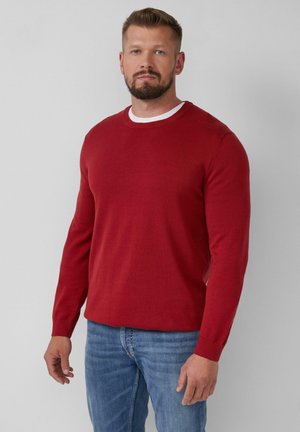 Pull en tricot rouge avec des manches longues et un col rond. Présente une bordure blanche autour du col, une texture douce et une coupe standard.