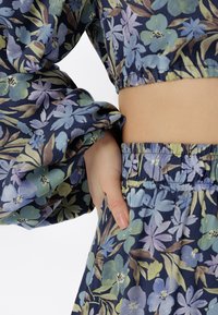 Set di top e gonna floreali in navy, con fiori blu e verdi, vita elasticizzata e maniche a sbuffo con dettagli arricciati.